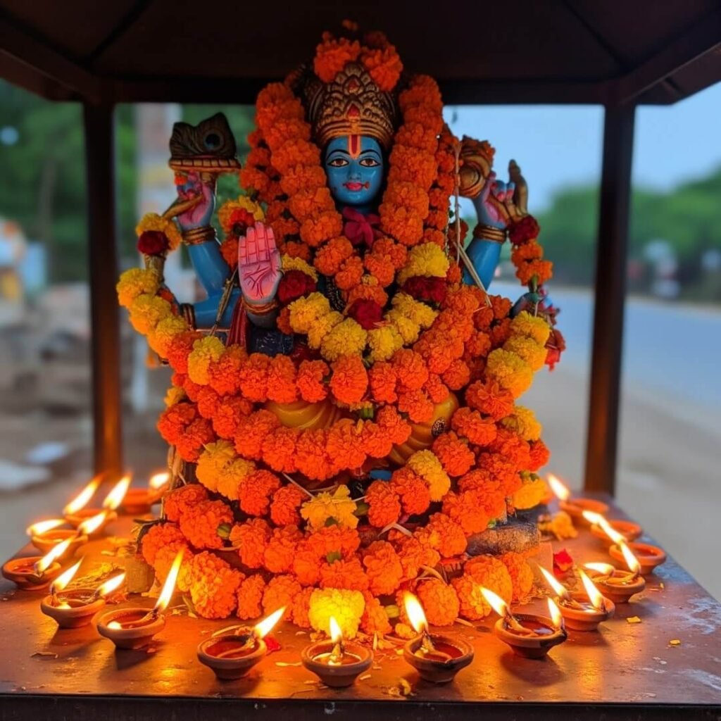 Vishnu idol in a roadside shrine, covered in marigolds.