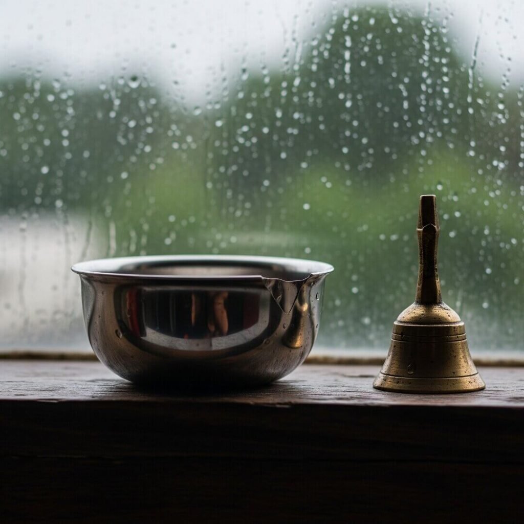 Chipped bowl, brass bell, and rain-streaked window.