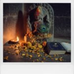 Ancient Secrets of Hindu Devotion You Should Know Temple idol with peacock feather, petals, book, and diya.